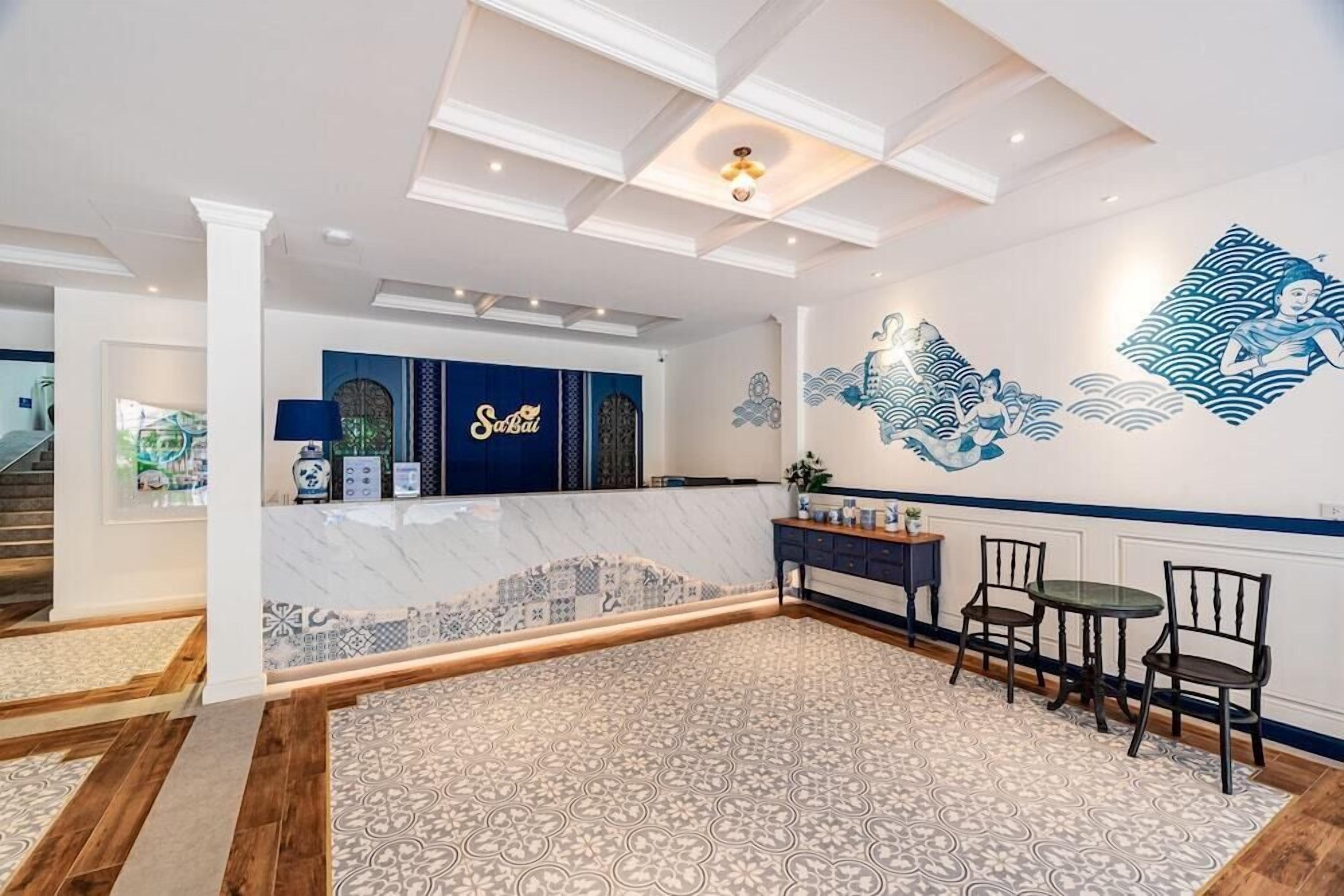 A hotel lobby with a reception desk, patterned carpet, and a mural on the wall.