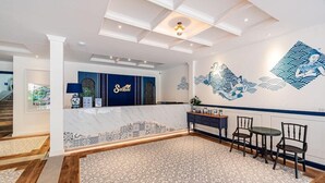 Een hotel lobby met een receptiebalie, een kamerbreed tapijt met patroon en een muurschildering.