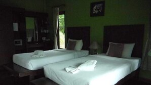A hotel room with two single beds, a wooden bench, a desk with a chair, a mirror, and a window with curtains. - Supsangdao Resort (Krabi)