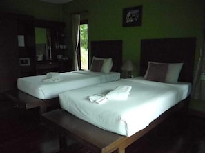 A hotel room with two single beds, a wooden bench, a desk with a chair, a mirror, and a window with curtains. - Supsangdao Resort (Krabi)