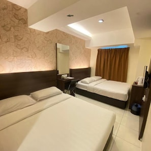 A hotel room with two beds, a desk, a chair, a mirror, and a window with curtains. - The Regency Garden Hotel (Ipoh)