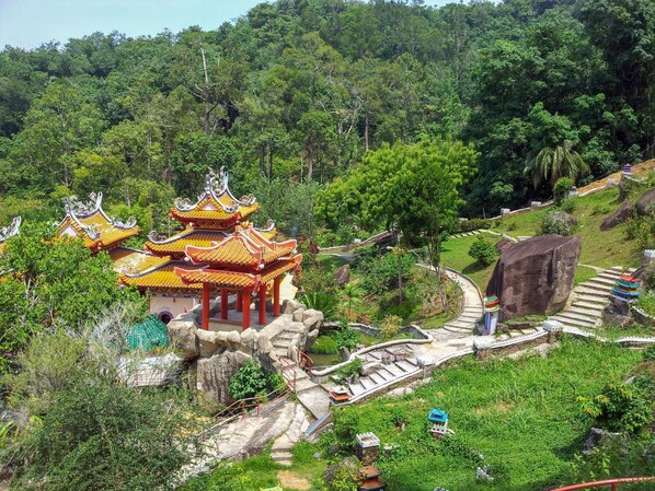 A traditional multi-tiered pagoda with ornate roof tiles, surrounded by lush greenery and a stone pathway leading to it.