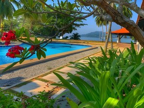 A swimming pool surrounded by tropical vegetation and a view of the sea. - Puteri Bayu Beach Resort (Kampong Pasir Bogak)