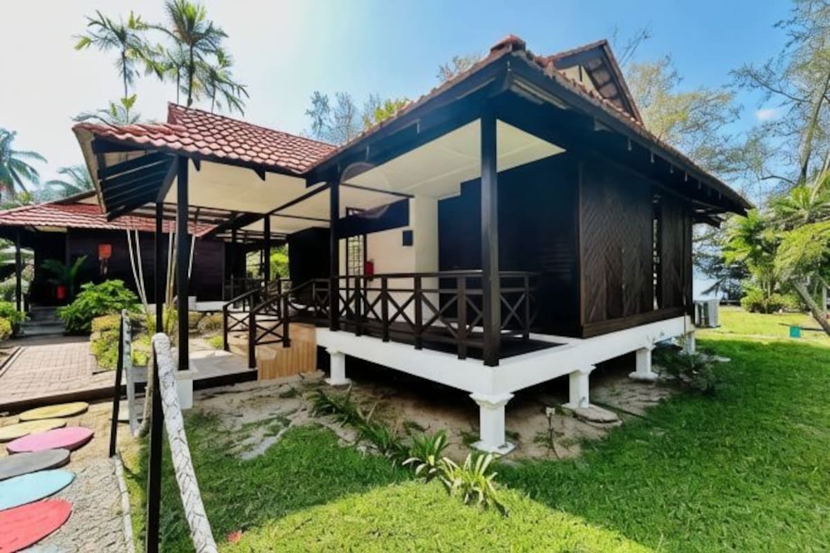 A two-story building with a covered porch and a small garden area.