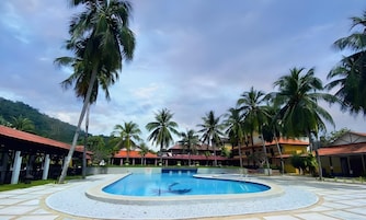 Una piscina rodeada de palmeras y edificios con tejados rojos.
