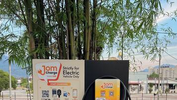 Una estación de carga para vehículos eléctricos, con un cartel que detalla el proceso de carga e información de contacto para soporte.