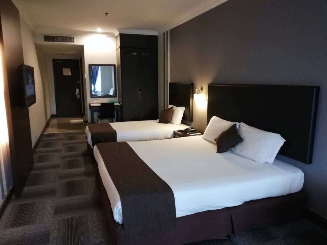 A hotel room with two beds, a desk, a chair, a TV, and a mirror.