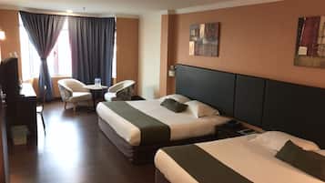 Habitación de hotel con dos camas, un escritorio, una silla y una mesita.