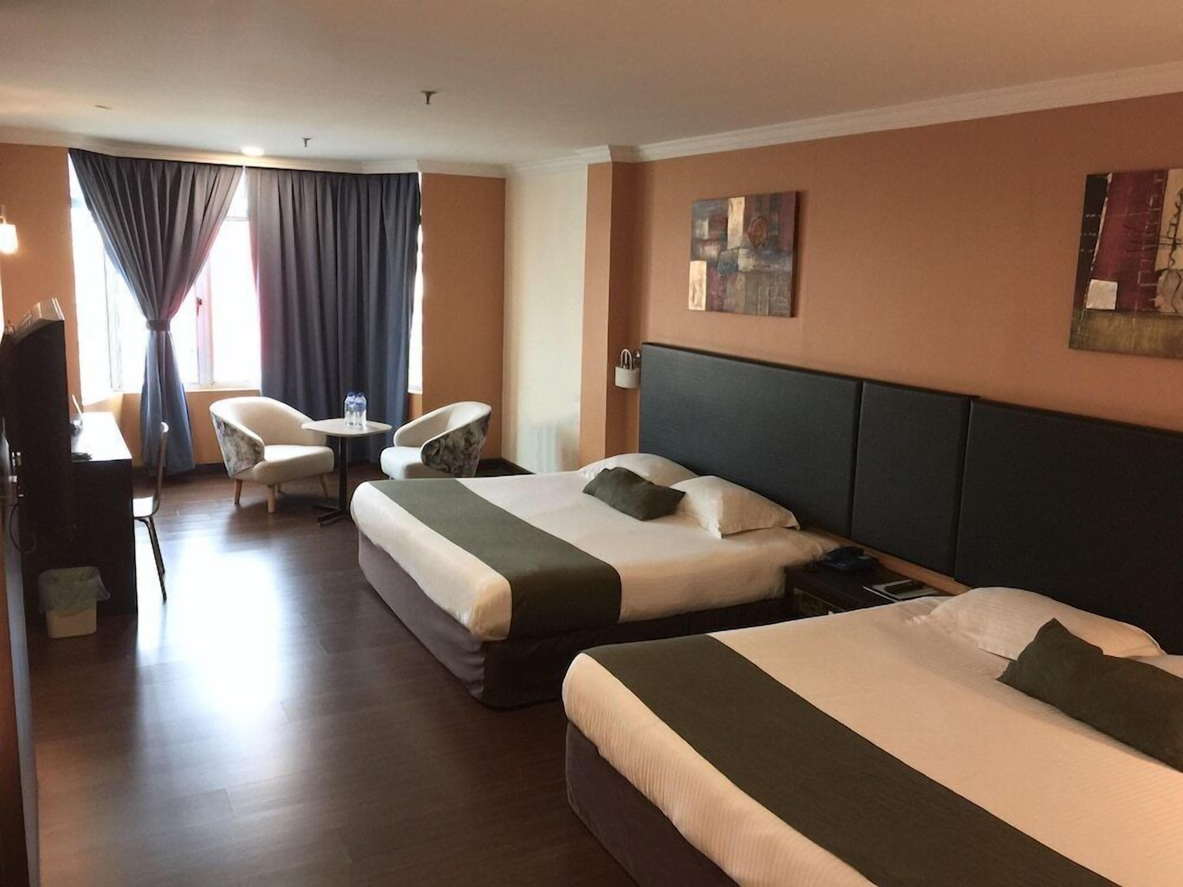 Una habitación de hotel con dos camas, un escritorio, una silla y un televisor.