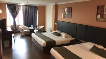 Una habitación de hotel con dos camas, un escritorio, una silla y un televisor.
