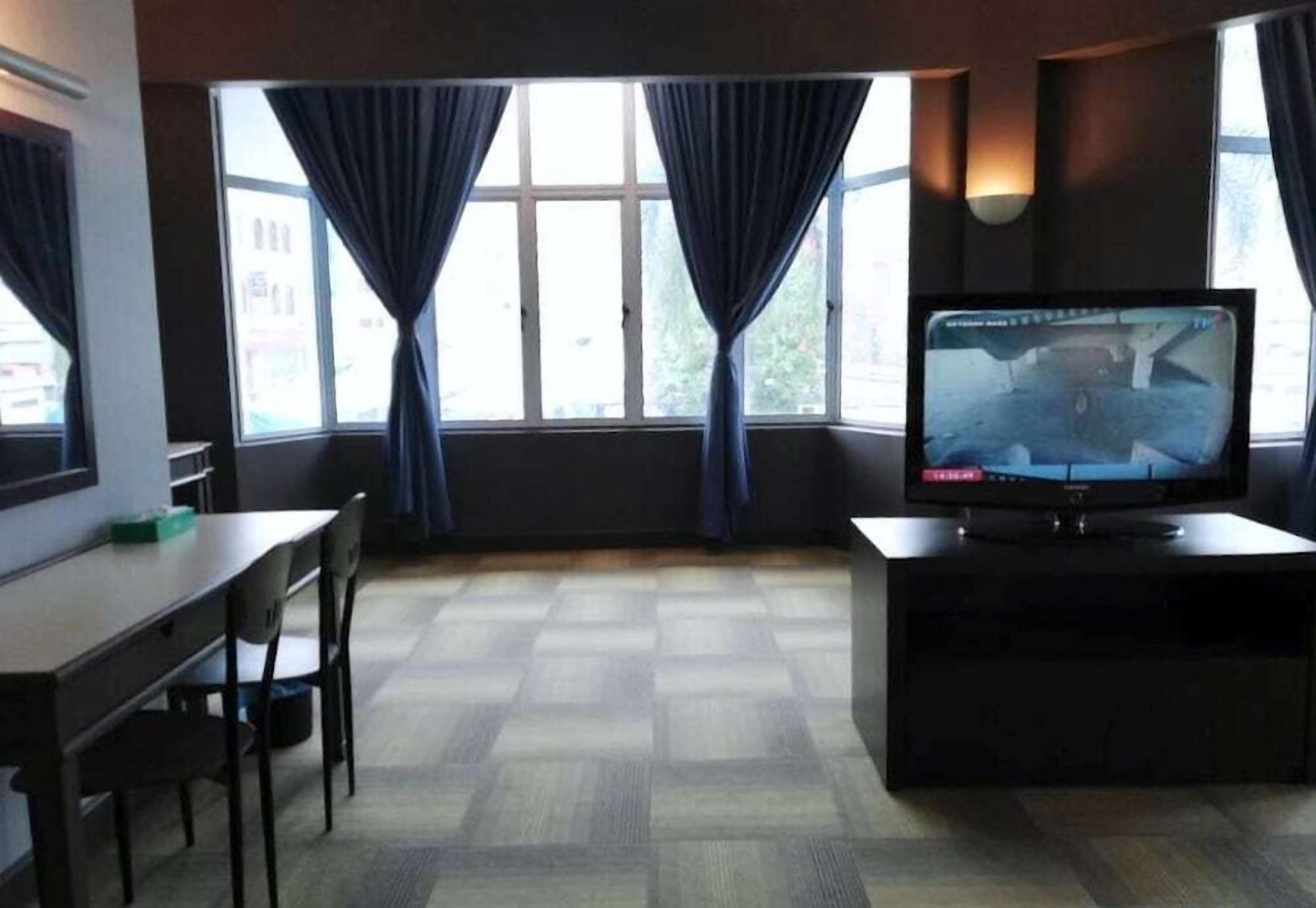 A room with a large window, a television, a table, and chairs.