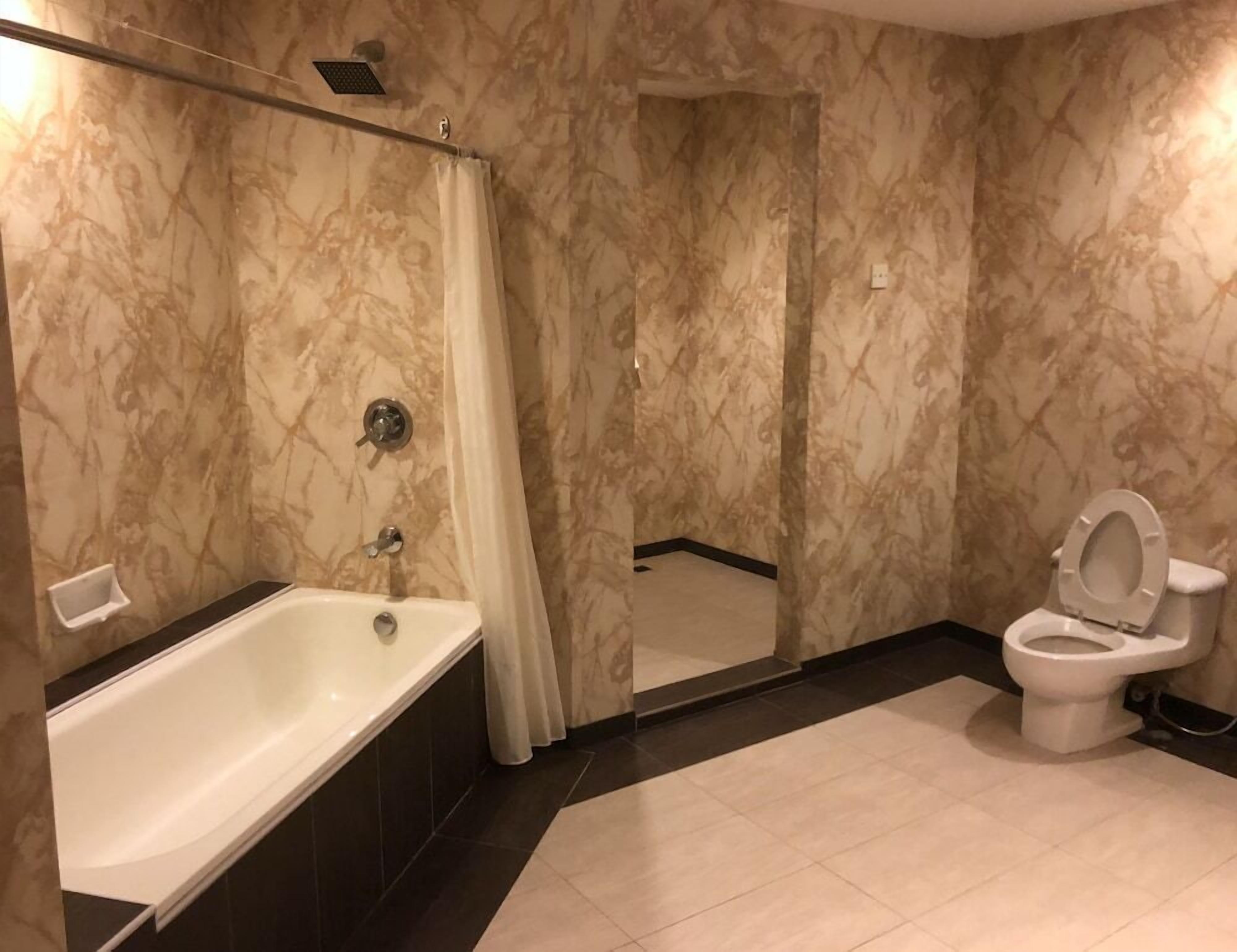 Un baño con bañera, inodoro y cortina de ducha.