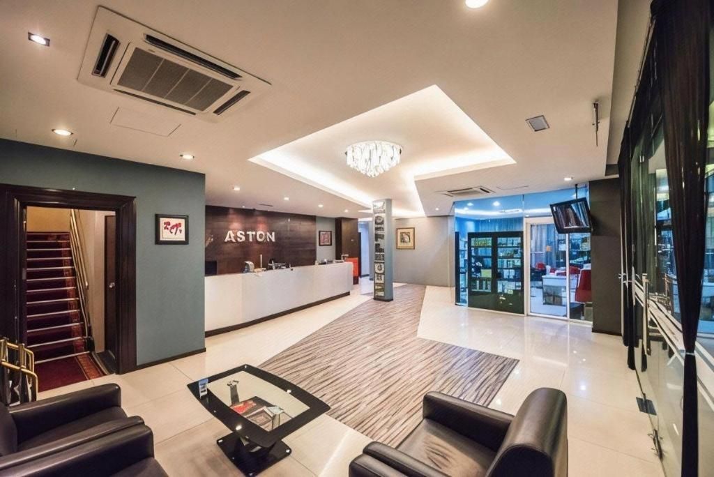 A hotel lobby with a reception desk, seating area, and a staircase leading to another floor.