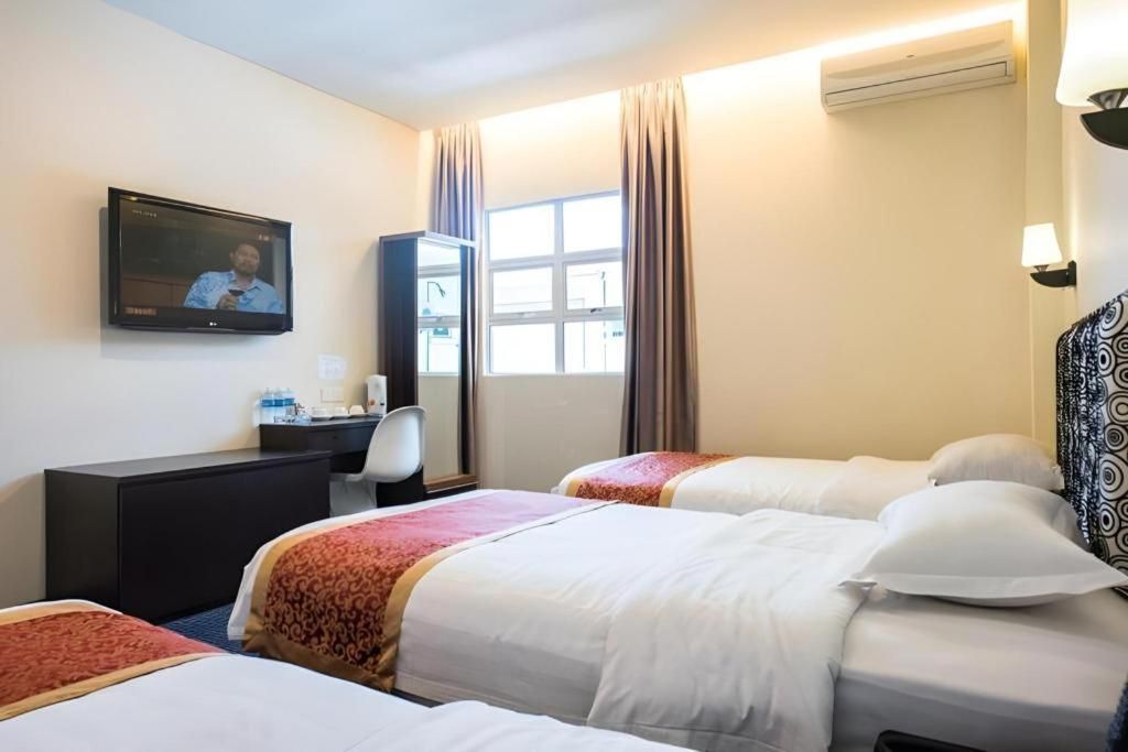 A hotel room with two beds, a desk with a chair, a television, and a window with curtains.