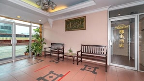 A hotel lobby with a reception desk, two wooden benches, a potted plant, and a framed artwork on the wall. - Holiday Park (KOTA KINABALU)