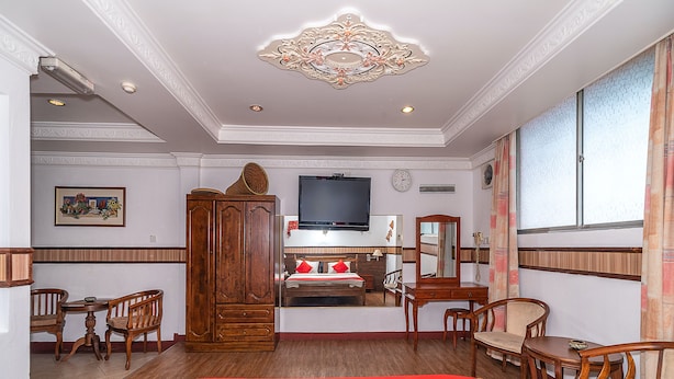A hotel room with a large bed, wooden furniture, a television, a clock, and a window with curtains. - Holiday Park (KOTA KINABALU)