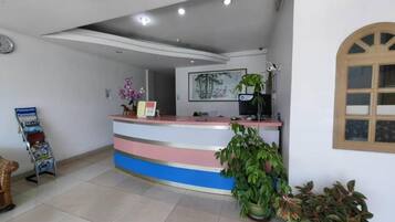 A reception desk with a 'Welcome' sign, a clock, and a framed picture on the wall.