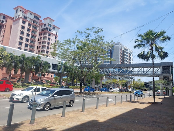 A multi-story residential building with balconies, a pedestrian overpass, and palm trees. - Celyn City Hotel (Kota Kinabalu)