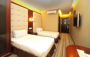 A hotel room with two beds, a TV, an air conditioner, and a door. - Celyn City Hotel (Kota Kinabalu)