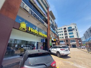 Un edifici de diversos pisos amb diverses botigues a la planta baixa, incloent-hi un 'Hello Market' i una botiga de records de 'Kota Kinabalu'.