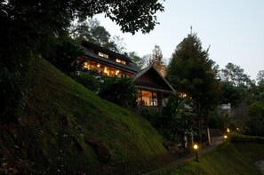A hillside house with multiple levels, surrounded by lush greenery and a pathway leading to the entrance. - Kangsadarn Resort & Waterfall (Chiang Mai)