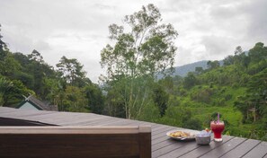 A wooden deck with a table set for a meal, overlooking a lush green landscape with trees and hills. - Kangsadarn Resort & Waterfall (Chiang Mai)