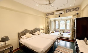 A hotel room with a large bed, a desk, a chair, a lamp, and a TV. - Lake Pichola (Udaipur)