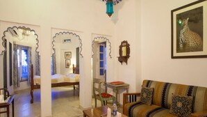 A traditional room with a bed, a sofa, a coffee table, and a framed picture of a leopard. - Lake Pichola (Udaipur)