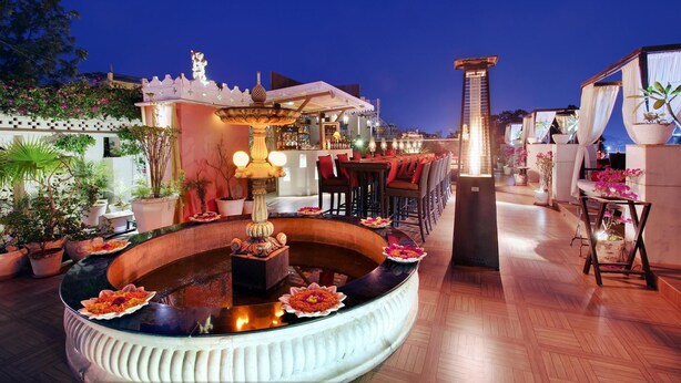 Una terrazza sul tetto con una fontana decorativa, zone relax e piante in vaso.
