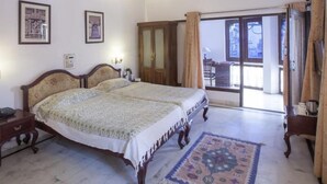 A bedroom with a double bed, a wooden wardrobe, and a large window with curtains. - Lake Pichola (Udaipur)