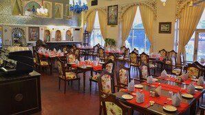 A restaurant with multiple tables set for dining, each with chairs and table settings. - Lake Pichola (Udaipur)