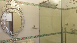 Un bagno con cabina doccia in vetro, un lavabo con specchio decorativo e una fascia floreale sulle pareti.