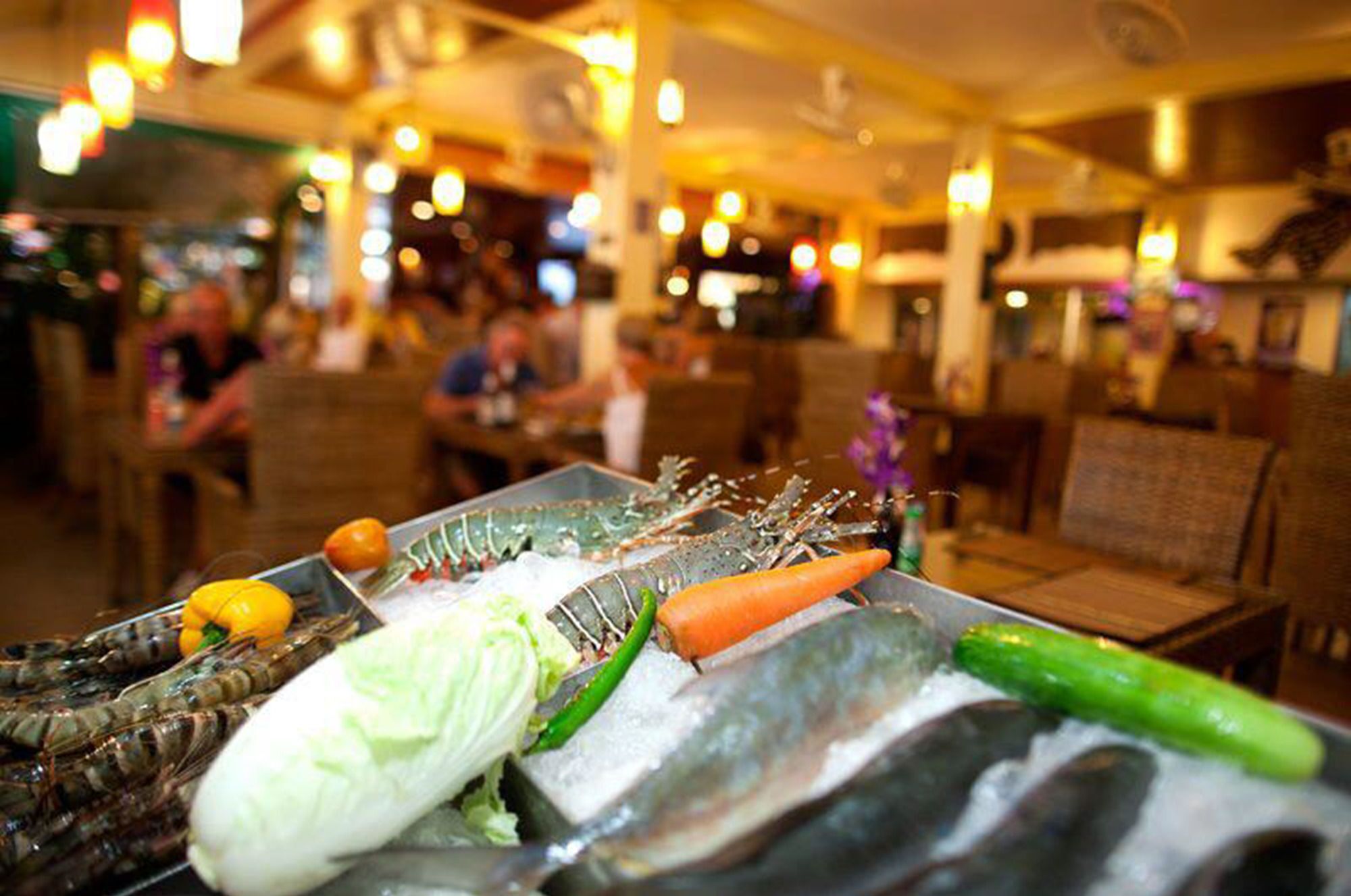 Una presentació de marisc amb diversos ingredients frescos com peix, pastanagues i lletuga.