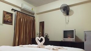 A hotel room with a bed, a TV, an air conditioner, and a fan. - MD House (Chiang Mai)