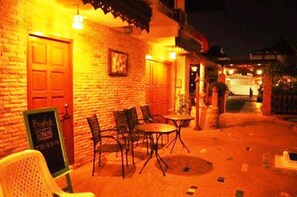 An outdoor seating area with brick walls, wooden doors, and tables and chairs. - MD House (Chiang Mai)