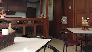 A restaurant with wooden furniture, a bar area, and a clock on the wall. - MD House (Chiang Mai)