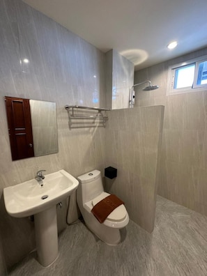 Et moderne badeværelse med vask, toilet og brusebad.