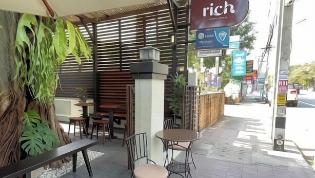 Un área de estar al aire libre con mesas y sillas, un banco y un letrero que dice "rich".