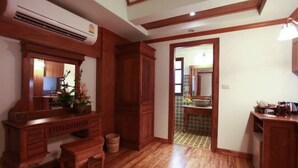 Una habitación con piso de madera, un banco empotrado, un armario de madera y un acceso a un baño con piso de cerámica.