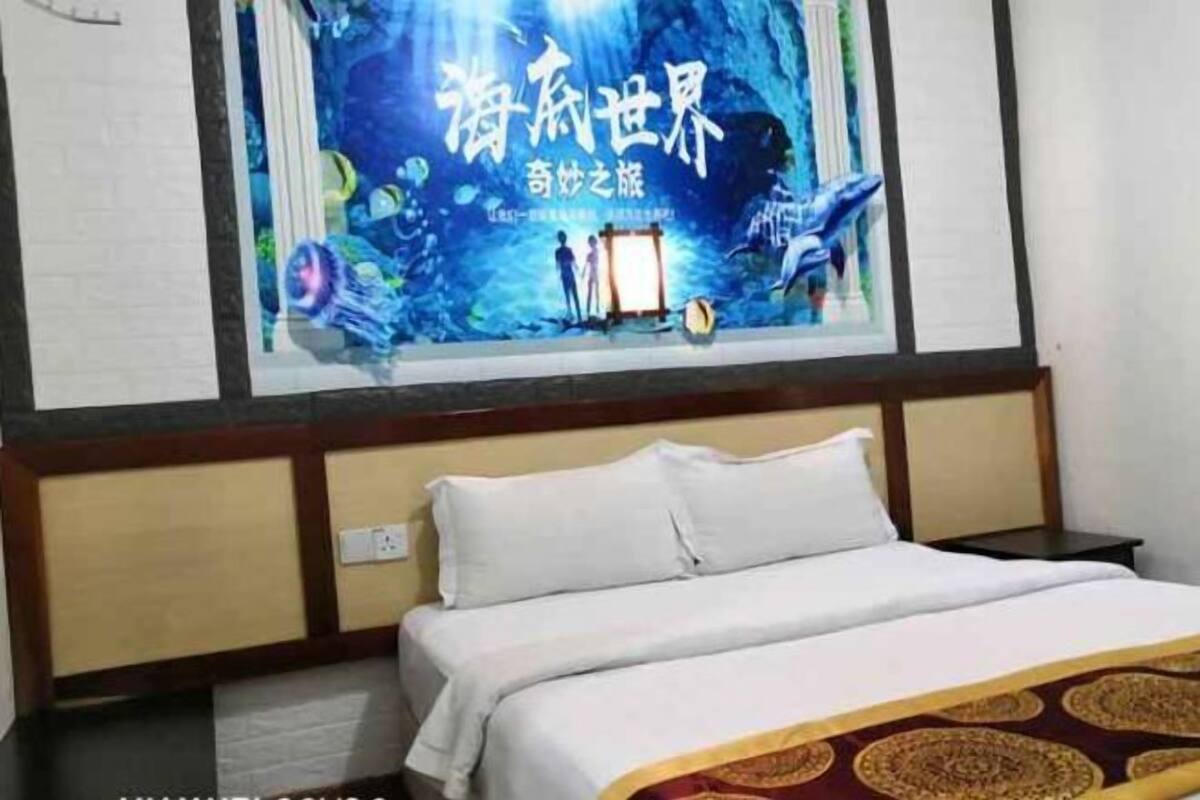 A hotel room with a bed, a nightstand, and a wall with a poster.