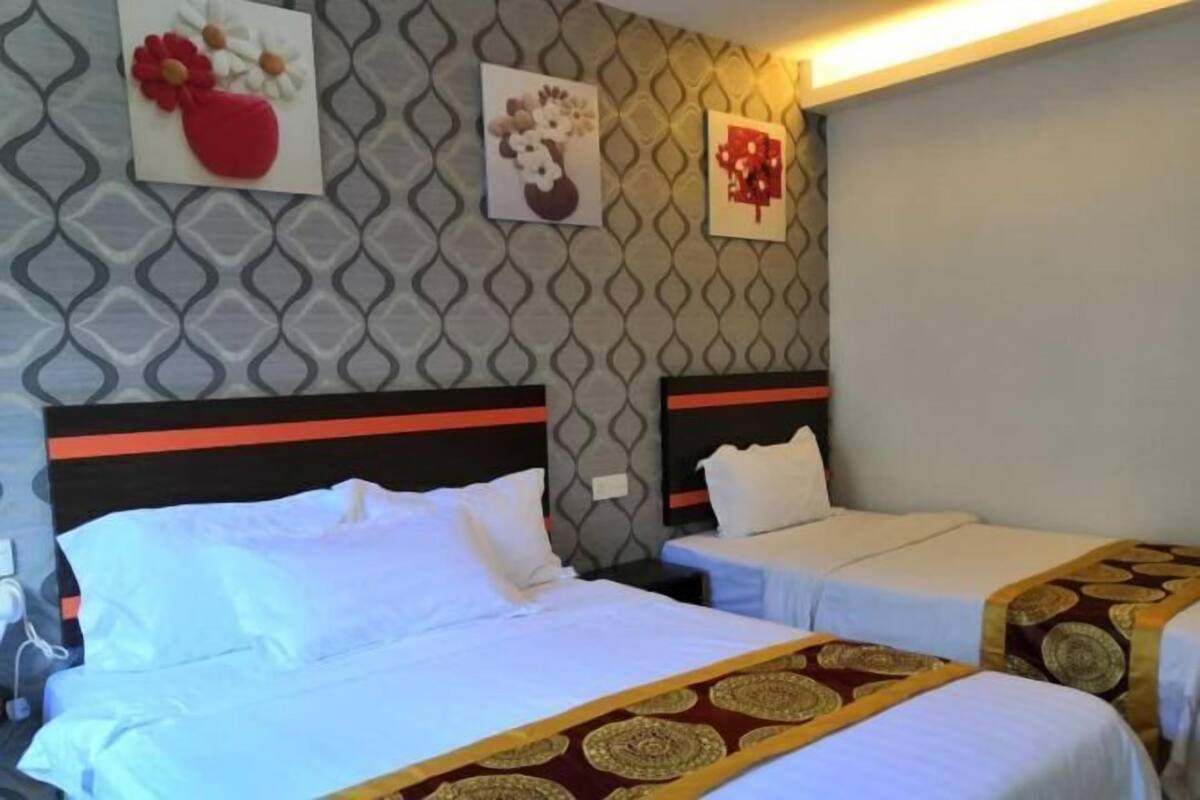 A hotel room with two beds, each with a headboard and a bedside table. There are wall-mounted artworks depicting flowers.