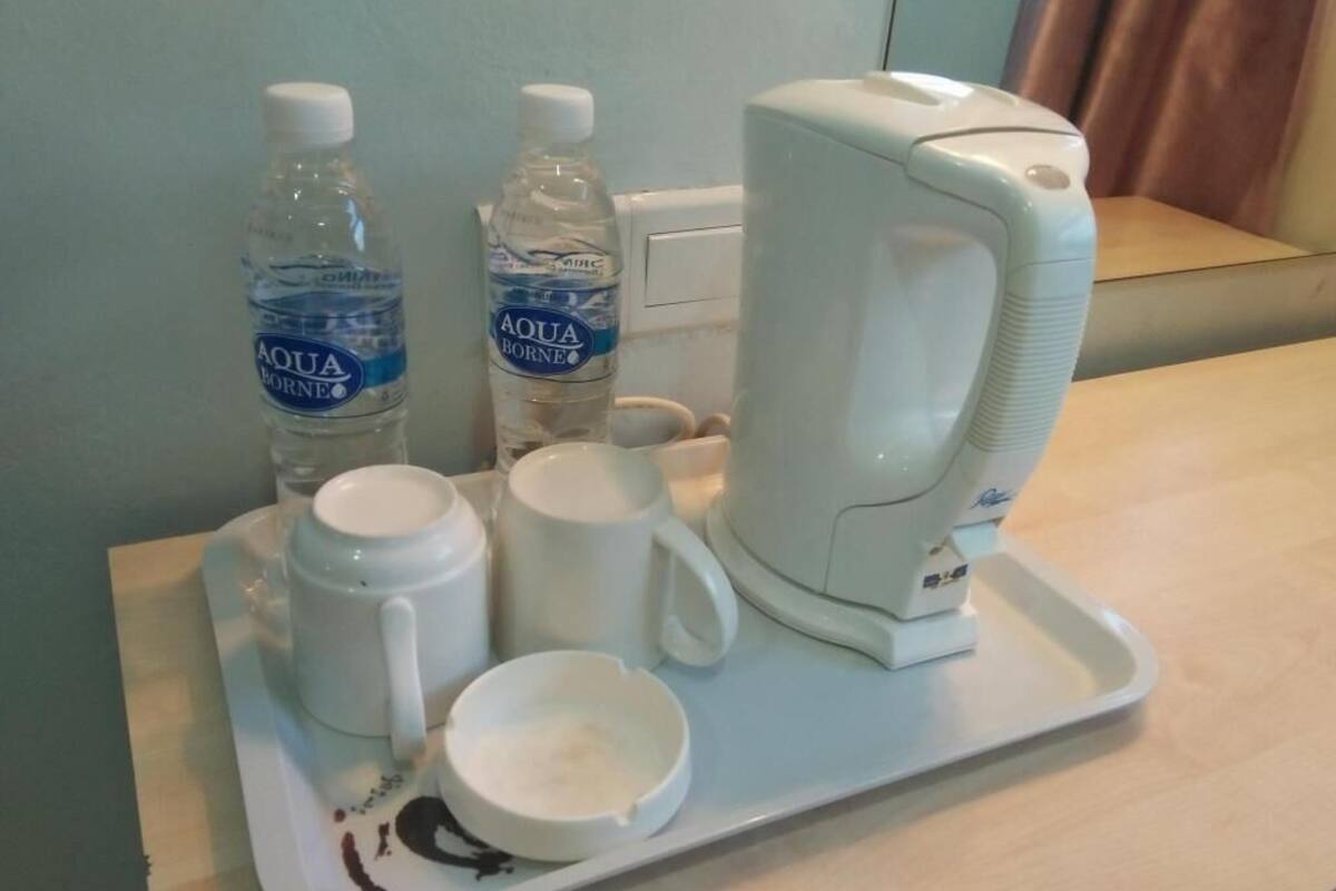 A tray with two water bottles, a coffee maker, a mug, and a cup on a table.