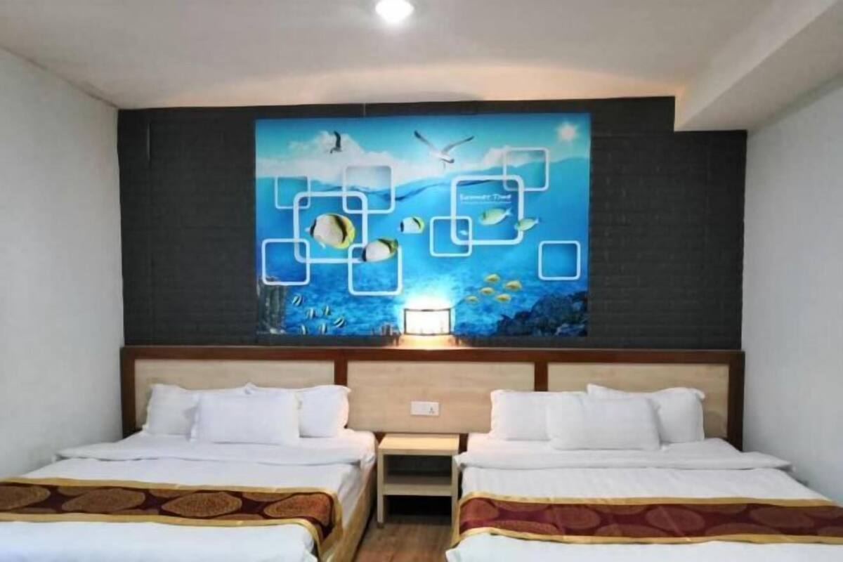 A hotel room with two beds, a mural of fish and sea life, and a night light.