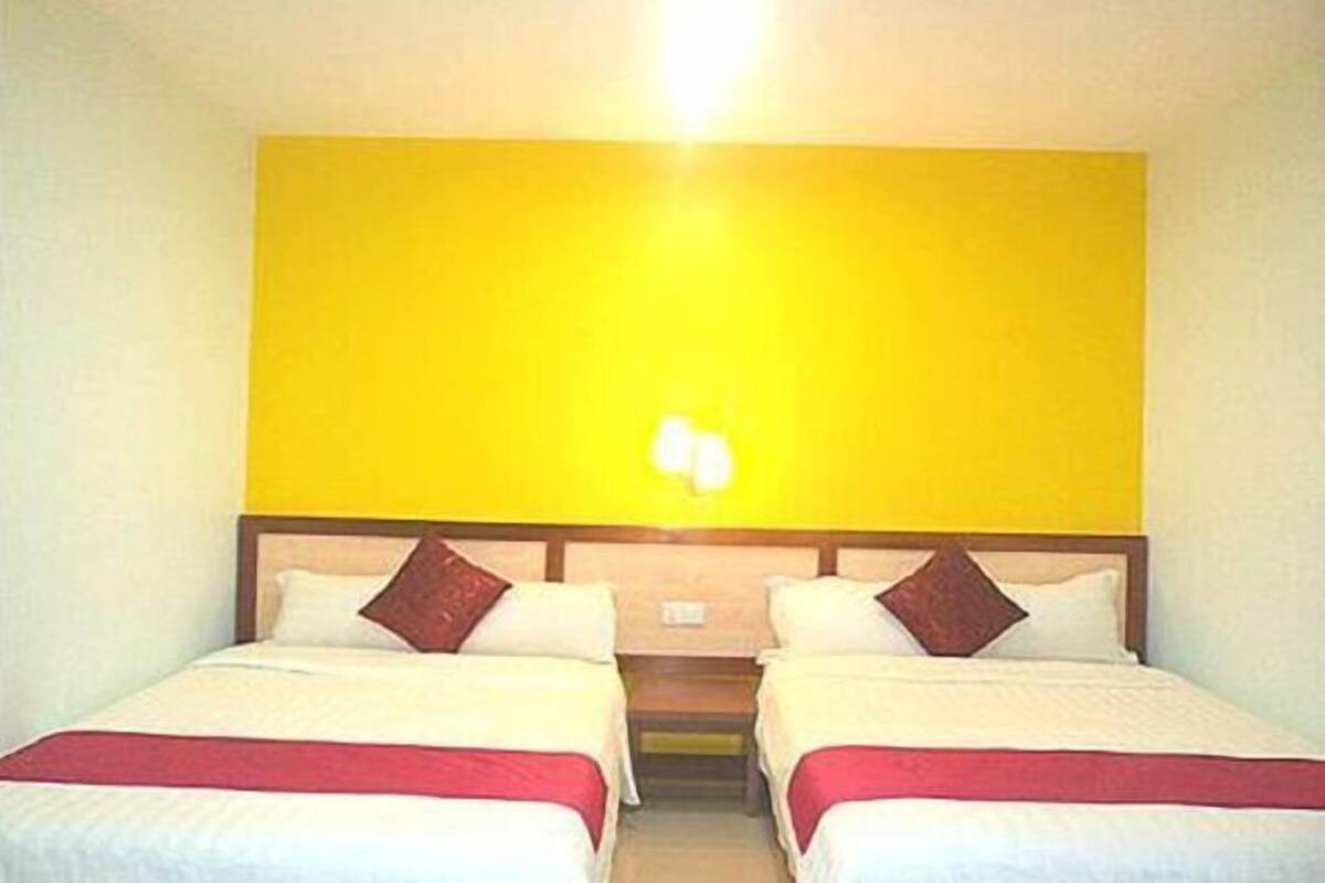 A room with two beds, each with a wooden headboard and white bedding.