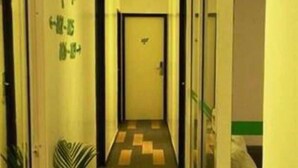 Un couloir d’hôtel avec un sol carrelé, des portes en verre et une porte au bout.