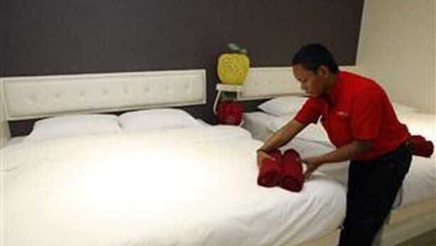 Une chambre d’hôtel avec un lit bien fait, une tête de lit et un fruit posé sur la table de chevet.