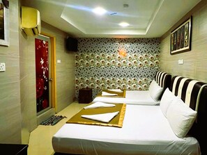 A hotel room with two beds, a patterned wallpaper, a red decorative panel, and a framed picture on the wall. - Batu Caves Business Hotel (Batu Caves)