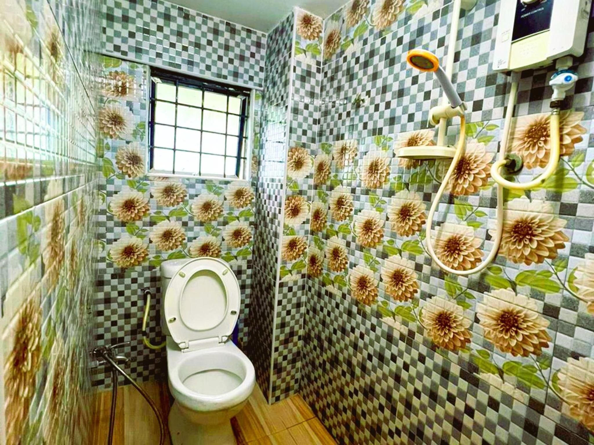 A bathroom with a toilet, a window, and a shower area.