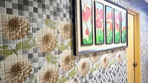 Een gang met een zwart-wit geruit tegelpatroon en bloemenmotieven op de muur.