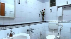 Une salle de bain avec des carreaux blancs, un lavabo, des toilettes et un miroir.
